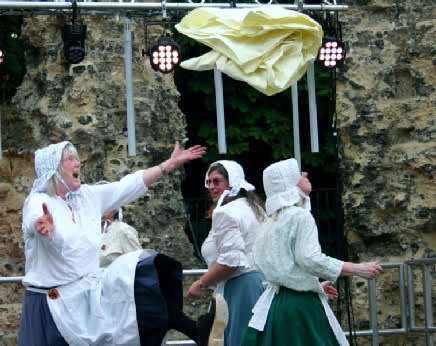 Dancers in action. Three women in traditional clothing are shown in an outdoor venue, each positioned differently as per the current dance choreography.